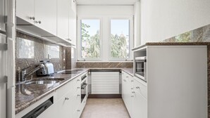 A modern kitchen with white cabinets, granite countertops, a built-in oven, and a window providing natural light. - Weinegg 4.5 Room w/ Storage & W/D, 2 mins to Mkt (Zurich)