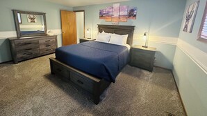 Ein Schlafzimmer mit Bett, Schminktisch, Nachttischen und einer Deckenleuchte.