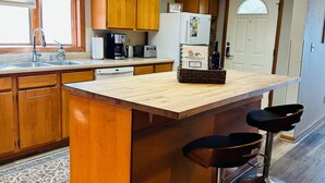 Eine Küche mit Holzausstattung, einer zentralen Kochinsel mit Barhocker, Dachfenstern und einem Kühlschrank.