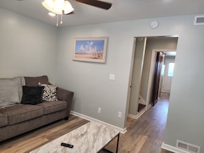 A living room with a couch, a remote control on a coffee table, a ceiling fan, and a painting on the wall. - Harrison Hotel Unit I
Pet Friendly
2nd Story (Murrells Inlet)