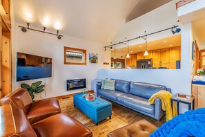 A living room with a sofa, ottoman, and a flat-screen TV.