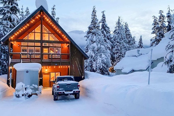 Cozy mountain chalet with warm lighting amidst a winter wonderland setting.