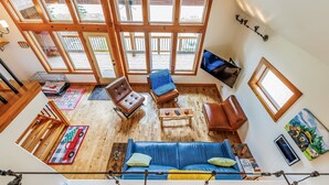 A spacious loft with a high ceiling, large windows, a blue sofa, a brown leather chair, and a wooden floor. - Feature: Skiing, Sledding, Snoqualmie Summit East (Snoqualmie Pass)