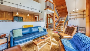 A spacious living area with a high ceiling, wooden staircase, and a large blue sofa. - Feature: Skiing, Sledding, Snoqualmie Summit East (Snoqualmie Pass)