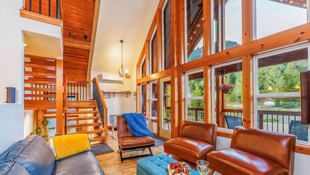 A spacious living area with a staircase, wooden beams, and large windows offering a view of the outdoors. - Feature: Skiing, Sledding, Snoqualmie Summit East (Snoqualmie Pass)