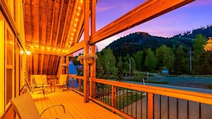 A wooden deck with chairs and hanging lights, overlooking a forested valley. - Feature: Skiing, Sledding, Snoqualmie Summit East (Snoqualmie Pass)