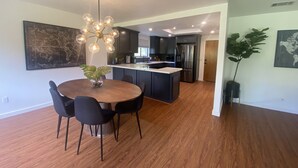 A modern kitchen with dark cabinets, a stainless steel refrigerator, and a central island. - Arroyo Manor - Centrally Located (Redding)