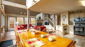 Amplia sala de estar con una mesa de comedor de madera, sofás rojos y una cocina equipada con electrodomésticos modernos.