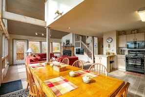 Amplia sala de estar con una mesa de comedor de madera, sofás rojos y una cocina equipada con electrodomésticos modernos.