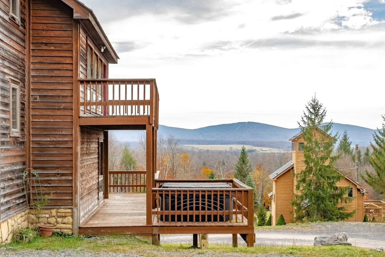 A wooden cabin with a balcony overlooking a mountainous landscape.