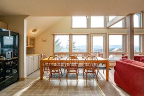 A dining area with a table and chairs, a kitchen with a refrigerator, and a red sofa.