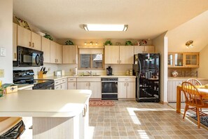 A kitchen with light wood cabinets, a black refrigerator, a microwave, a stove, and a dishwasher.