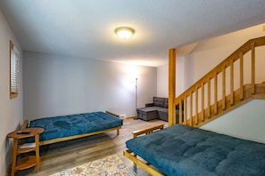 Una habitación con dos camas individuales, un sofá, una lámpara de pie y una escalera de madera.