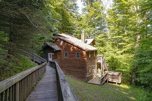 Una baita di legno con una veranda e una scala che conduce a un portico.