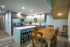 Una cucina moderna con isola centrale, tavolo da pranzo in legno e sgabelli da bar.