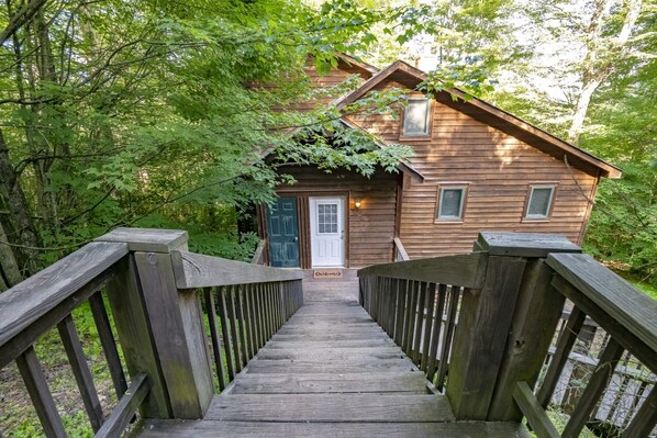 A wooden cabin with a front door, a small porch, and a wooden staircase leading up to it. - Robin`s Perch - 318 Northpoint Way (Davis)