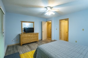 Un dormitorio con cama, cómoda, espejo y ventilador de techo.