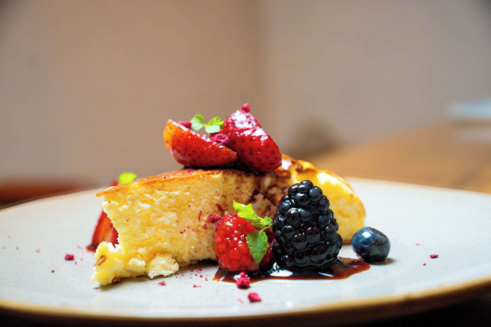 A dessert plate with a slice of cake, strawberries, and blueberries.