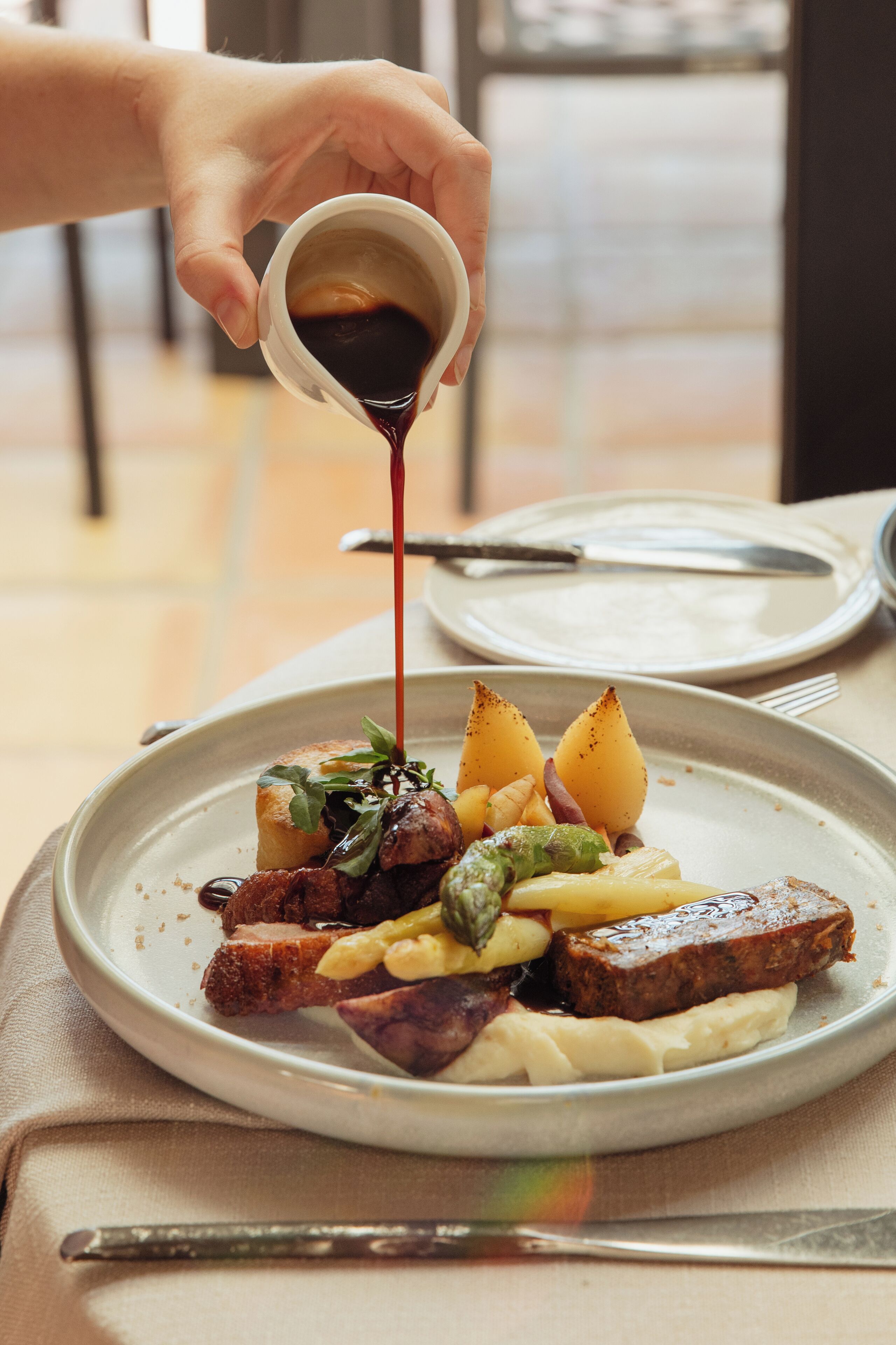 A plate of food with a sauce being poured over it.