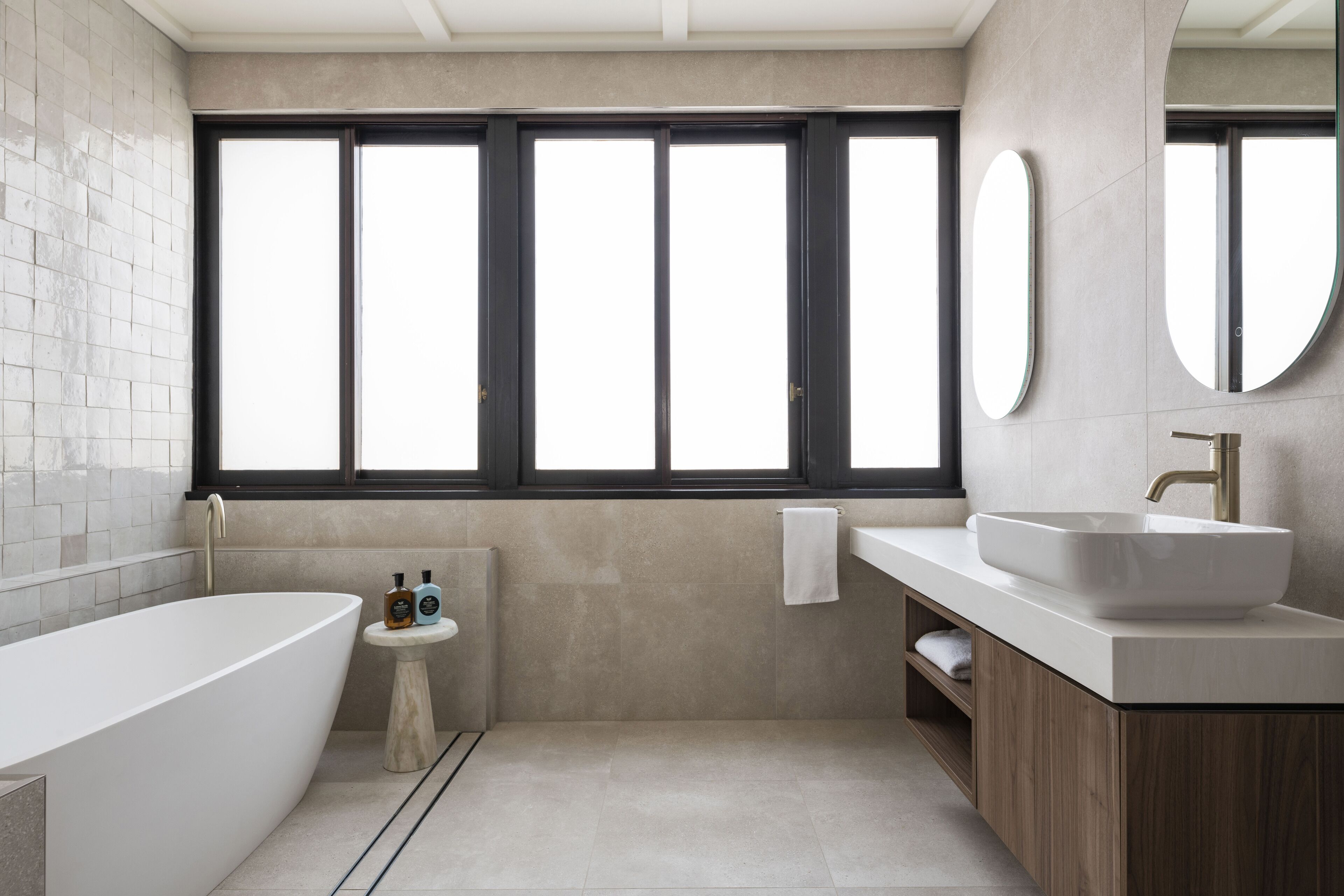 A modern bathroom with a freestanding bathtub, a vanity with a large sink, and a window with multiple panes.