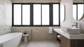 A modern bathroom with a freestanding bathtub, a vanity with a large sink, and a window with multiple panes.