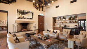 A cozy living room with a fireplace, comfortable seating, and a wine bar with shelves of bottles. - Tower Lodge (Pokolbin)