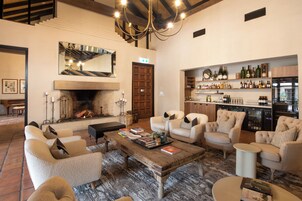 Una sala de estar acogedora con chimenea, asientos confortables y una barra de vinos con estantes llenos de botellas.