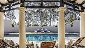 A poolside area with lounge chairs, a pergola, and a view of the pool. - Tower Lodge (Pokolbin)