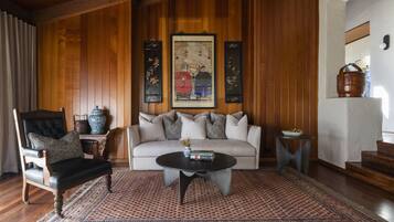 A living room with a sofa, a chair, a coffee table, a patterned rug, and a painting on the wall.