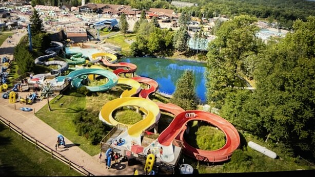 Ein Wasserpark mit mehreren Rutschen und einem See im Hintergrund.