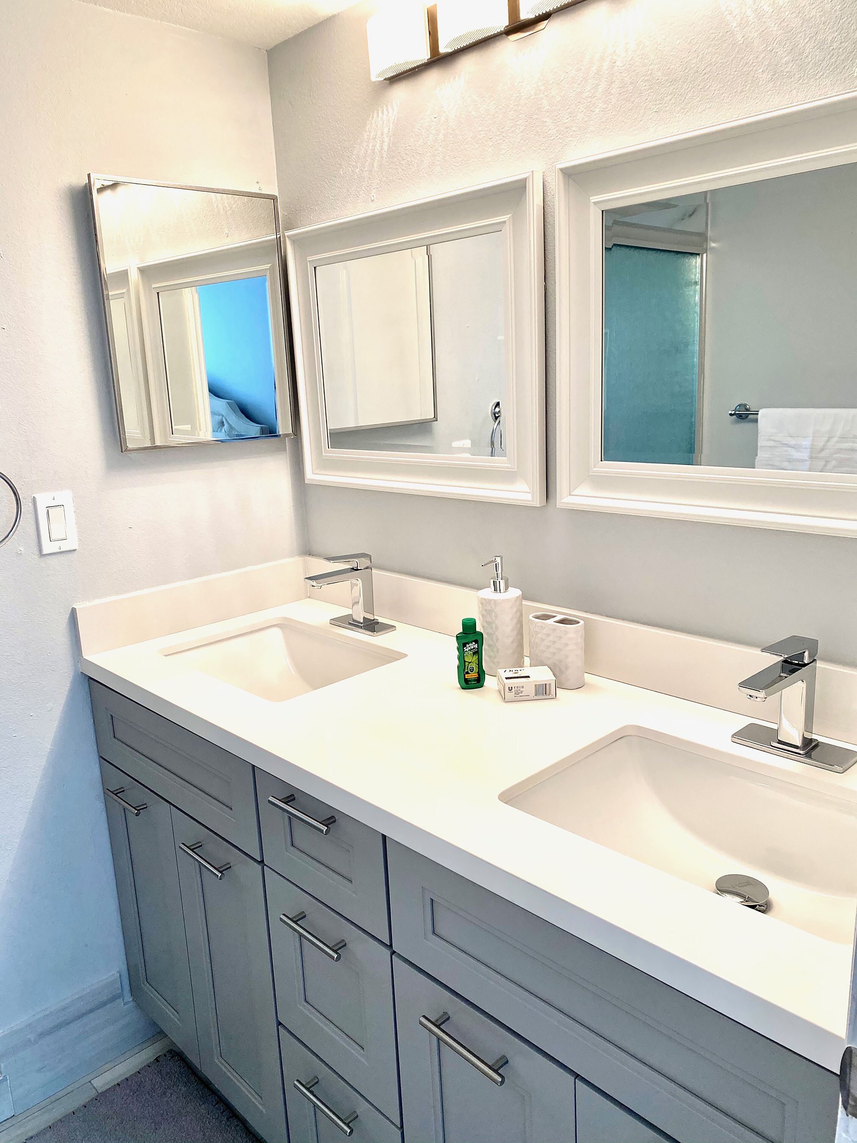 A bathroom with two sinks, a mirror, and a cabinet.