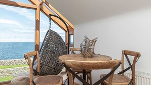 Ein Holzesstisch mit vier Stühlen, einem Hängesessel und einer dekorativen Fischskulptur.