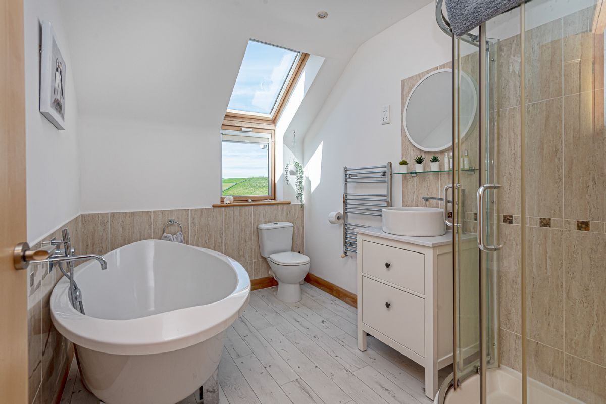 A modern bathroom with a freestanding bathtub, a glass-enclosed shower, and a toilet.