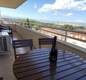 Ein Balkon mit Tisch, Stühlen und einer Weinflasche.