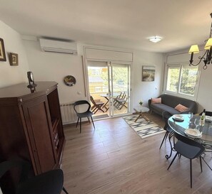A spacious living area with a dining table, sofa, and a view through a sliding glass door to an outdoor patio.