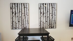 A dining area with a dark wooden table and benches, flanked by two birch bark wall art pieces. - Beautiful 2BR Suite just off Main St, Picton, near Sandbanks (Prince Edward)