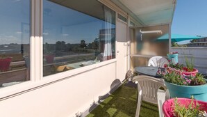 A balcony with a white chair, a small table, and potted plants. - Beautiful apartment for 4 people with WIFI, balcony and pets allowed (Bruges)