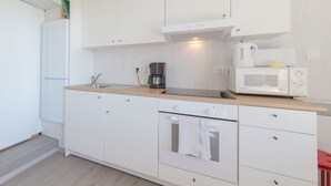 A modern kitchen with white cabinets, a wooden countertop, a coffee maker, a microwave, and a small oven. - Beautiful apartment for 4 people with WIFI, balcony and pets allowed (Bruges)