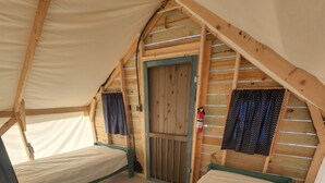 Una tienda acogedora de una sola habitación con interior de madera, un banco verde y una puerta con cortina.