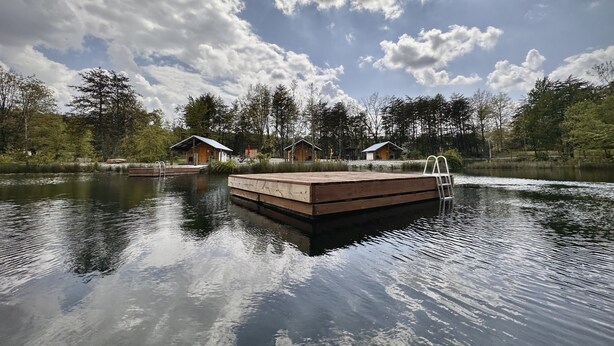 Un muelle de madera que se adentra en un lago tranquilo, con un cielo despejado.