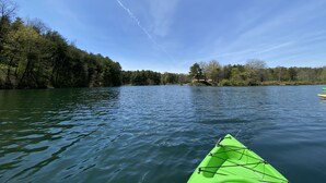 Un río tranquilo con un kayak verde en primer plano y un cielo despejado.