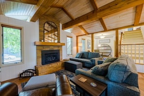 A cozy living room with a fireplace, wooden beams, and comfortable seating.
