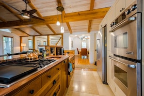 A kitchen with wooden beams, a gas stove, an oven, and a refrigerator.