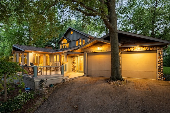 A two-story house with a stone facade garage, a covered porch, and a well-maintained driveway.