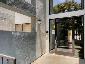 Enter a contemporary space with a sleek glass door and covered outdoor area.