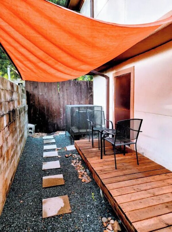 Relax in a secluded patio area with a wooden deck, stepping stones, and a metal chair and table.