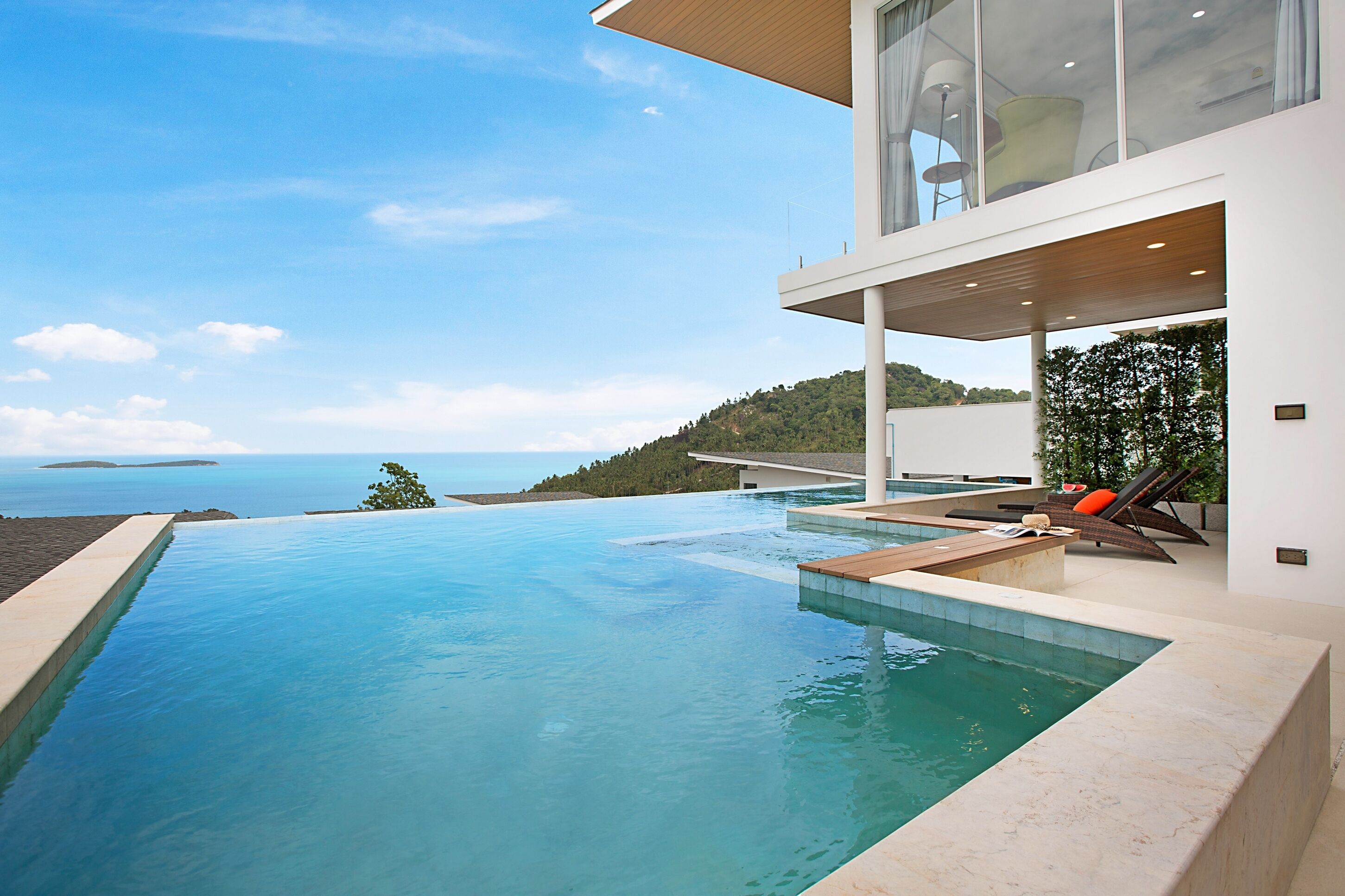 A modern house with a large infinity pool overlooking the sea.