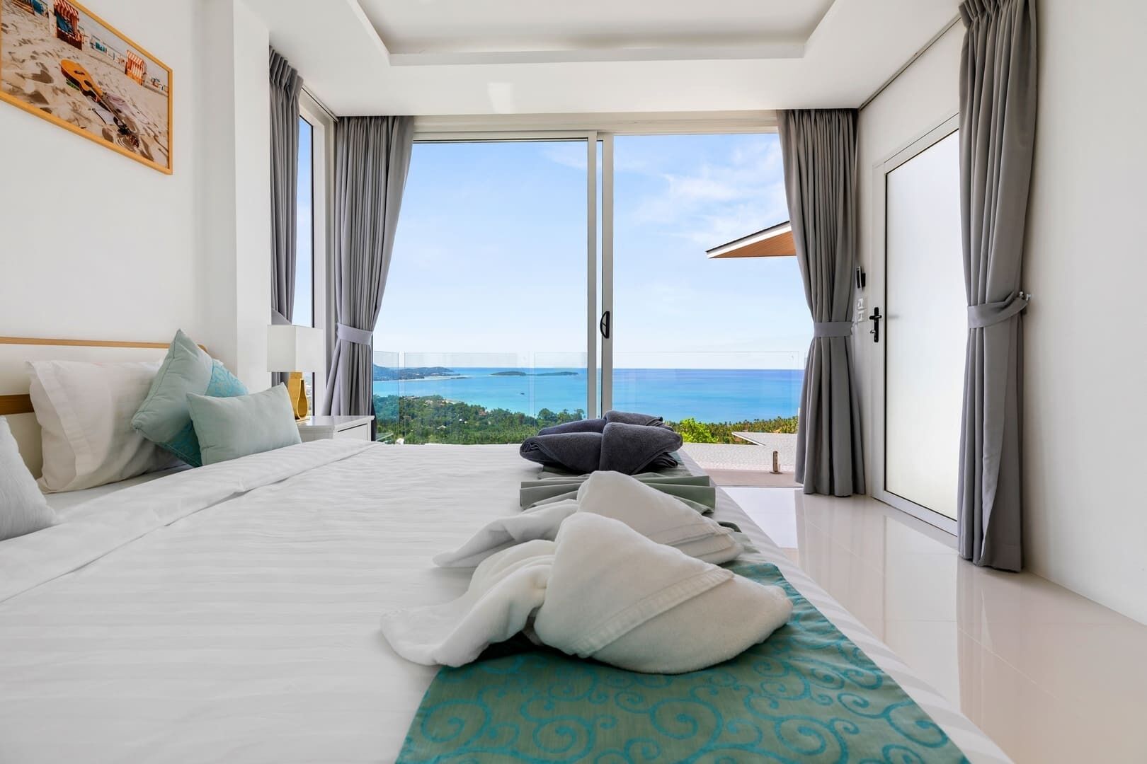 A bedroom with a large bed, a view of the sea, and a balcony.
