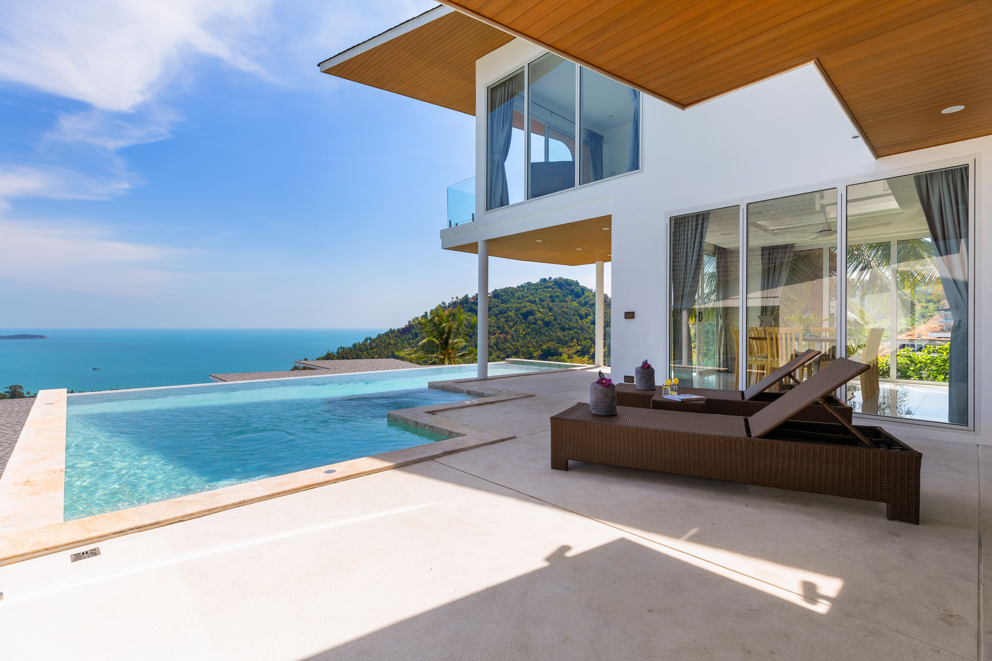 Une maison moderne dotée d’une grande piscine et offrant une vue sur la mer.