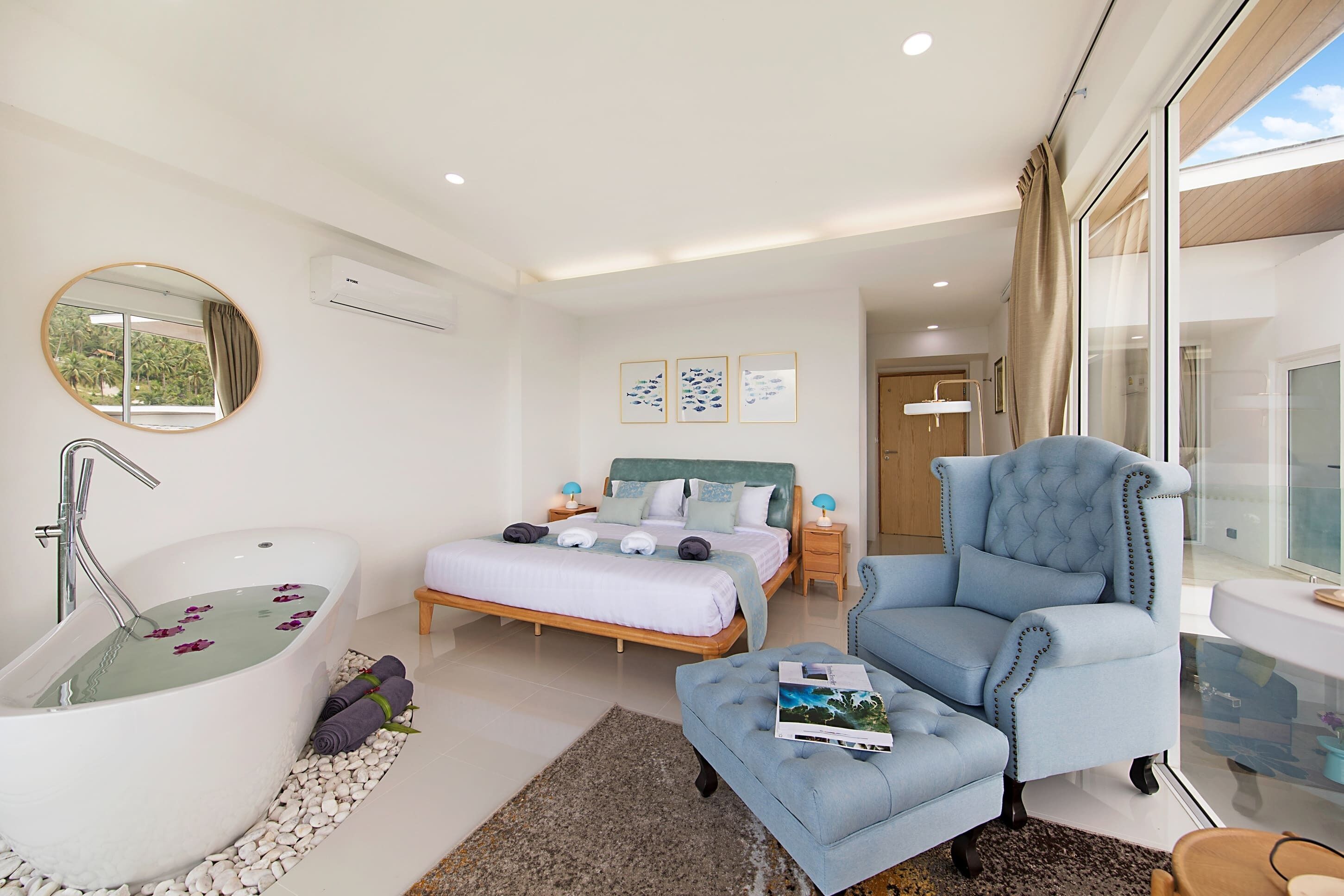 Une chambre à coucher moderne avec un grand lit, un coin salon et une baignoire.